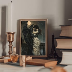 May include: A framed print of a romantic illustration depicting a winged figure embracing a woman in a flowing white dress. The scene is set against a dark, moonlit background with a hint of a cityscape in the distance.