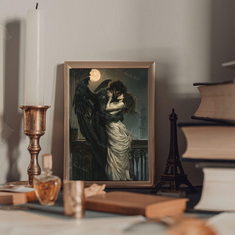 May include: A framed print of a romantic illustration depicting a winged figure embracing a woman in a flowing white dress. The scene is set against a dark, moonlit background with a hint of a cityscape in the distance.
