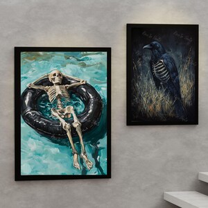 May include: A black and white painting of a skeleton floating in a blue pool on a black inner tube. The skeleton is wearing a relaxed pose with its arms behind its head. The painting is framed in black.