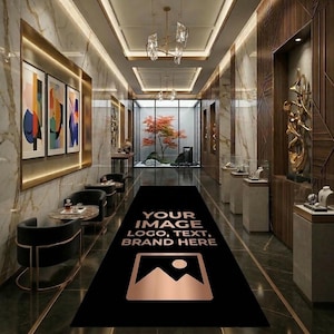 May include: A long black rectangular floor runner rug featuring a central graphic area for custom branding, including the text "YOUR IMAGE LOGO, TEXT, BRAND HERE" and a mountain icon in a metallic copper tone, centered in a luxury hallway.