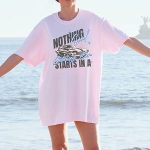 May include: A pink t-shirt with a graphic of a classic car and the text "Nothing good starts in a getaway car".