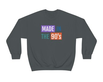 May include: A dark gray sweatshirt with the text "MADE IN THE 90'S" printed on the front in colorful boxes. The words "MADE" and "IN" are in purple boxes, "THE" is in a teal box, and "90'S" is in an orange box.