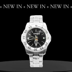 May include: A silver wristwatch with a black face and a silver band. The watch face has a white border with black numbers and a white triangle at the top. The watch face also has the words "LAS VEGAS" and "POLO CLUB" printed on it.