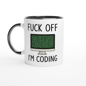 May include: White ceramic mug with a black interior and handle. The mug features the text "FUCK OFF" above "I'M CODING" in black, with a computer screen graphic in between. The screen displays a matrix of numbers.