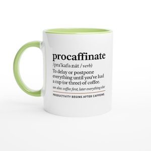 Puede incluir: Taza de café de cerámica blanca con asa y borde interior verdes. La taza presenta la palabra "procaffinate" con una definición, incluyendo la frase "LA PRODUCTIVIDAD COMIENZA DESPUÉS DE LA CAFEÍNA."