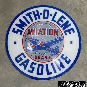 May include: A circular metal sign featuring a blue, white, and red color scheme. The text reads SMITH-O-LENE AVIATION BRAND GASOLINE. A blue and red airplane graphic is centered on a gray background. The word REPRODUCTION is printed at the bottom.