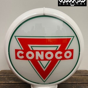 May include: A vintage-style Conoco gas station globe sign. The sign features a white frame with a green border and a red and white Conoco logo. The sign is round and has the text "Hot Rod Gasoline" in the upper right corner.