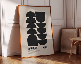 Op de afbeelding: Een ingelijste poster met een geometrisch ontwerp in zwart en wit. De poster toont een reeks overlappende halve cirkels in een gestapelde opstelling. De tekst "Bauhaus 1969" is onderaan de poster gedrukt.