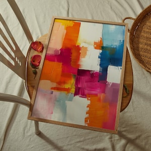 Può includere: Dipinto astratto con pennellate audaci di vernice arancione, rosa, rossa, blu e gialla su una tela bianca. Il dipinto è incorniciato in una cornice di legno naturale.