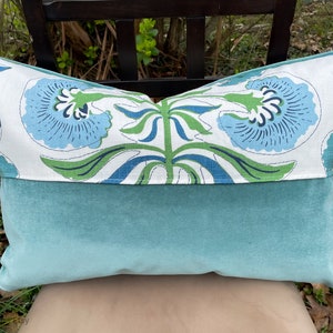 May include: A decorative pillow with a blue and green floral pattern on one side and a solid teal velvet on the other side.