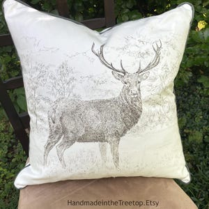 May include: A square decorative pillow with a deer illustration. The pillow features a detailed drawing of a stag in a forest setting, with a gray border and the text "HandmadeintheTreetop.Etsy" at the bottom.