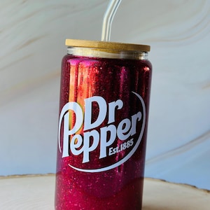 May include: A red glitter tumbler with a white Dr Pepper logo and the text "Est. 1885". The tumbler has a bamboo lid and a clear plastic straw.