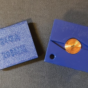 May include: A blue plastic mold with a copper coil inside. The mold has the text "24GA 20MM" printed on it.