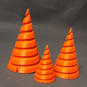 May include: Three orange 3D printed spiral cones of varying sizes. The cones are made of a smooth, plastic-like material and have a textured surface.