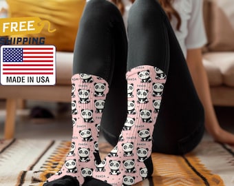 Op de afbeelding: Een paar roze en zwarte sokken met een herhalend patroon van schattige pandaberen. De sokken hebben het woord "PANDA" erop gedrukt.