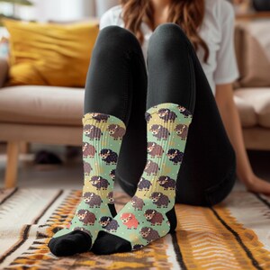 May include: A pair of colorful socks with a repeating pattern of cartoon yaks. The socks are green, brown, black, and orange. The socks are worn on a person's feet.