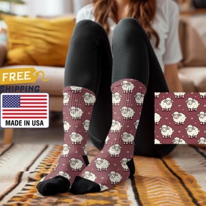 May include: A pair of red crew socks with a white sheep pattern. The socks are made in the USA and feature a cartoon sheep design.