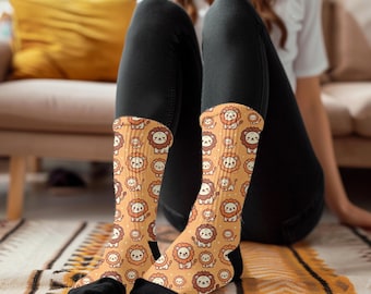 May include: A pair of socks with a pattern of cartoon lions on a yellow background. The socks are black and have a white cuff.
