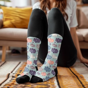 May include: A pair of blue and white socks with a pattern of cartoon hippos. The socks are on a person's feet and the person is sitting on a couch.