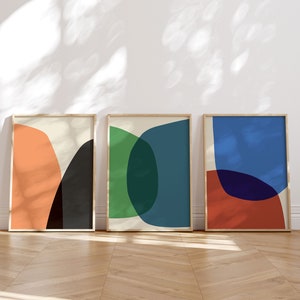 May include: Three framed abstract art prints with geometric shapes in shades of orange, black, green, blue, and red.