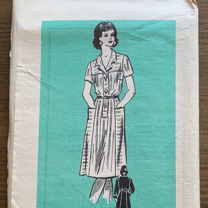 Puede incluir: Patrón de costura vintage para un vestido con cuello, mangas cortas y bolsillos. El patrón está impreso sobre un fondo azul claro e incluye instrucciones para las tallas 16 1/2. El patrón se titula "Patrón impreso" e incluye el número 4743.