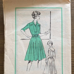May include: Vintage sewing pattern with a green dress illustration. The pattern shows a woman in a collared dress with a belt. Text reads "Alice Schweitzer, Prominent Designer, M 199 - SIZE 14". The pattern is for a size 14.