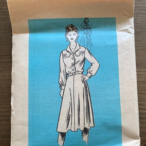 May include: A vintage sewing pattern for a dress. The pattern is printed on a light blue background and features a black and white illustration of a woman wearing the dress. The pattern number is 4626 and the size is 18 1/2. The text "Printed Pattern" is printed at the bottom of the pattern.