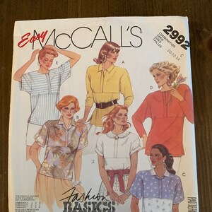 May include: A sewing pattern for a women's blouse with a variety of styles. The pattern is from McCall's and is called "Fashion Basics". The pattern number is 2992 and the sizes are 10-12-14. The pattern is for overlock (serger) sewing.
