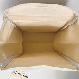 May include: A white canvas tote bag with a white fabric lining. The bag has a label on the bottom that says "little miss bliss".