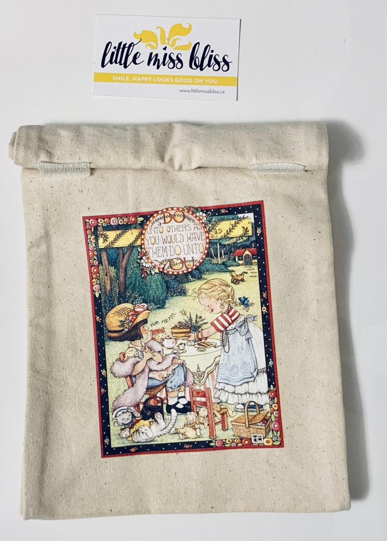 May include: A beige canvas tote bag with a colorful illustration of two girls having tea. The illustration includes the text "UNTO OTHERS AS YOU WOULD HAVE THEM DO UNTO" and "FOR ME".