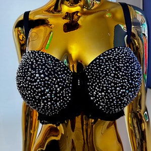May include: A black bra with a lace trim and a large number of rhinestones.