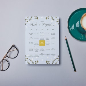 Puede incluir: Una tarjeta de bingo azul y blanca con el título "Pride & Prejudice Bingo". La tarjeta tiene un borde floral e incluye casillas con frases como "La Sra. Bennet dice algo vergonzoso" y "Lydia se escapa".