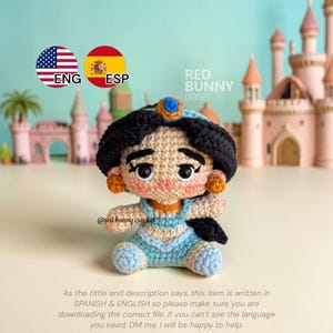 May include: A handmade crochet doll of a princess, featuring a blue outfit, black hair, and a blue and orange headpiece. The doll is set against a backdrop of a miniature castle. The text in the image says "RED BUNNY CROCHET".