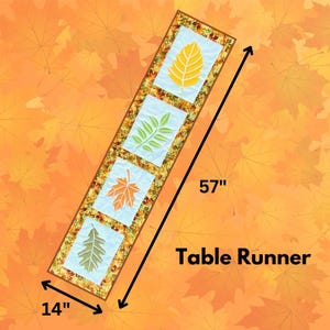 May include: A rectangular table runner, 145 cm long and 36 cm wide, features four light blue squares with leaf designs in yellow, green, and orange. The runner is bordered with a patterned fabric and the words "Table Runner".