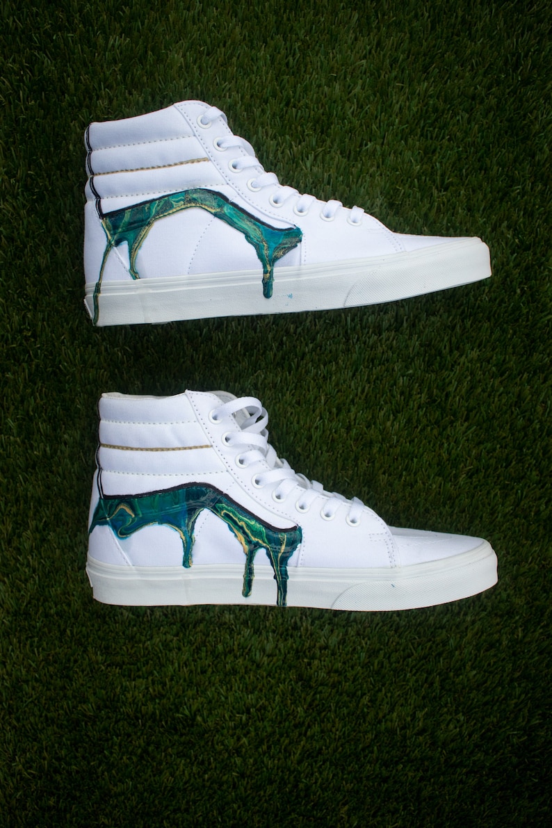 May include: White high-top trainers with green and gold paint dripping down the sides.