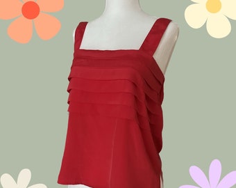 May include: A red sleeveless top with a square neckline and a layered ruffle detail. The top is made of a lightweight fabric and has a relaxed fit.