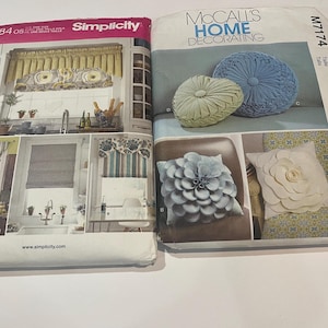 May include: Two sewing pattern envelopes side by side. The left envelope is Simplicity 684, featuring window valance designs. The right envelope is McCall's Home Decorating M7174, displaying various decorative throw pillows including round and floral shapes.