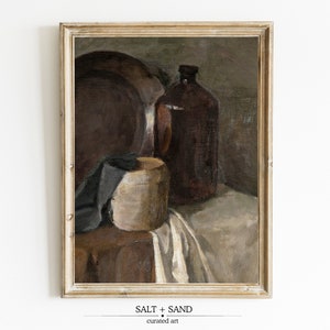 May include: A framed painting of a still life with a brown bottle, a wooden bowl, a cloth, and a plate. The painting is in a light brown frame.