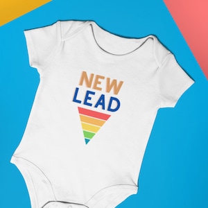 May include: White baby onesie with a rainbow triangle and the text "NEW LEAD" in blue and orange letters.