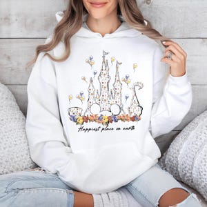 May include: White hoodie with a floral print of a castle and the text "Happiest place on earth".