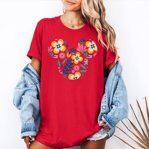Op de afbeelding: Rood T-shirt met een bloemig Mickey Mouse ontwerp. De bloemen zijn in tinten geel, roze, rood en blauw.