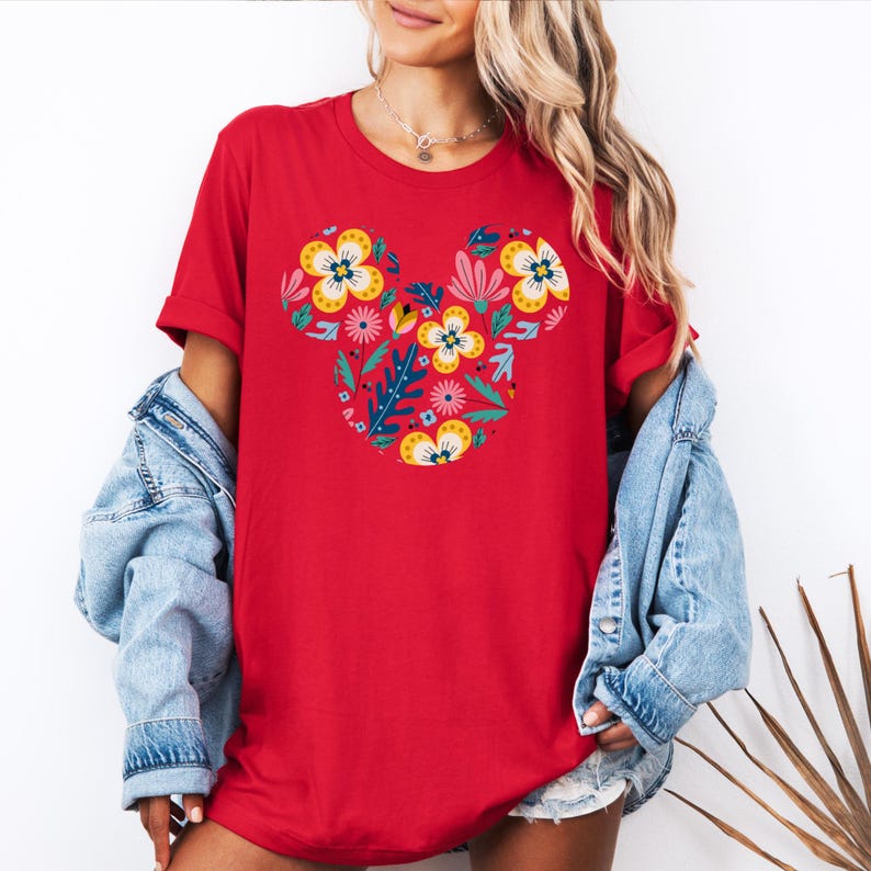 Op de afbeelding: Rood T-shirt met een bloemig Mickey Mouse ontwerp. De bloemen zijn in tinten geel, roze, rood en blauw.