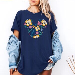 Op de afbeelding: Een marineblauw T-shirt met een bloemig Mickey Mouse-ontwerp. Het ontwerp bevat gele, roze en blauwe bloemen.