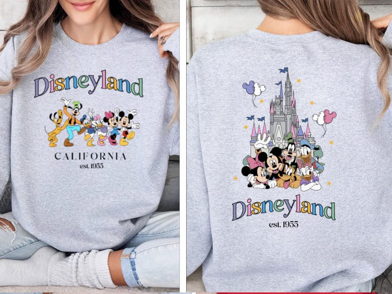 Puede incluir: Sudadera gris con un logotipo de Disneyland colorido y un gr&aacute;fico de Mickey Mouse y sus amigos. La parte posterior de la sudadera presenta un gr&aacute;fico colorido del castillo de Disneyland y Mickey Mouse y sus amigos.