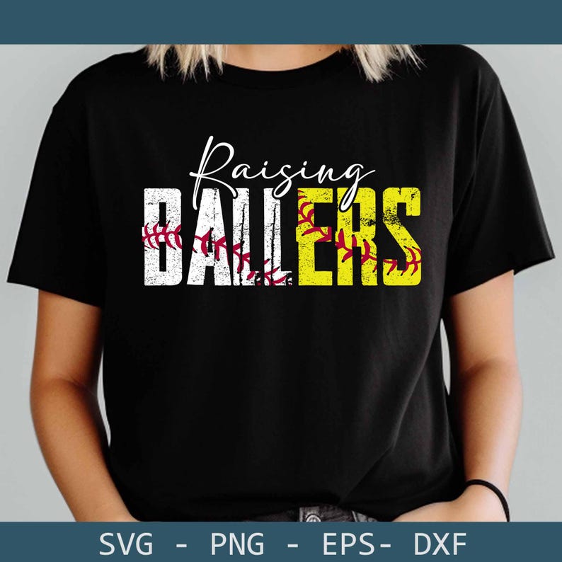 May include: Black t-shirt with the words "Raising Ballers" in white and yellow block letters. The word "Ballers" is in yellow with a softball design. The word "Raising" is in cursive. The shirt is a crew neck.