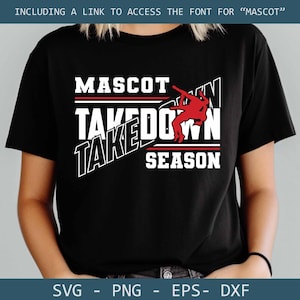 May include: Black t-shirt with the words "MASCOT TAKEDOWN SEASON" in white, red, and black. A red graphic of a wrestler is featured in the design. The shirt includes a link to access the font for "MASCOT".