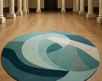 May include: A large, round area rug with a geometric design in shades of teal, blue, and light green. The rug is placed on a wooden floor in a room with columns and a high ceiling. The rug's design features curved lines.
