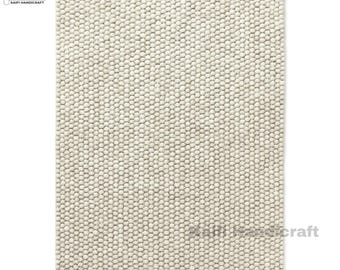 Pode incluir: Um tapete retangular branco sujo com uma superfície texturizada. O tapete é feito de pequenos elementos redondos e compactos, criando uma aparência densa e tátil. Adequado para uma sala de estar ou quarto. Medidas em centímetros.