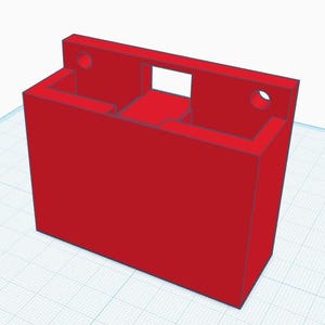 Könnte beinhalten: Ein roter rechteckiger Organizer mit einer rechteckigen Öffnung und zwei kreisförmigen Löchern. Der Organizer hat zwei Fächer und eine Rückwand. Das Objekt ist wahrscheinlich 3D-gedruckt.