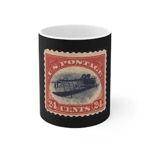 May include: Black coffee mug with a vintage US postage stamp featuring a blue airplane and the text "US POSTAGE 24 CENTS 24".